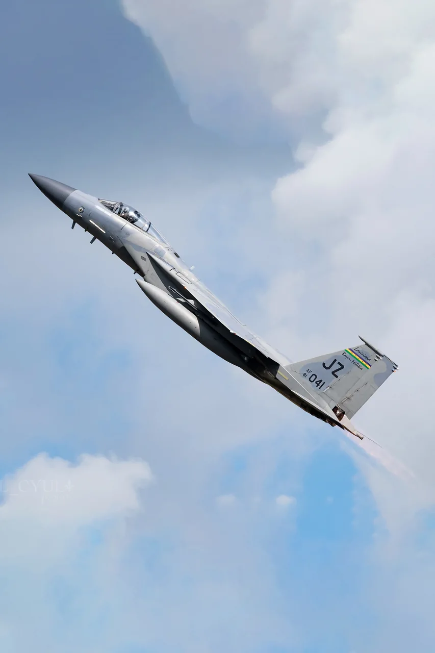 A fighter jet climbing through the pale sky.