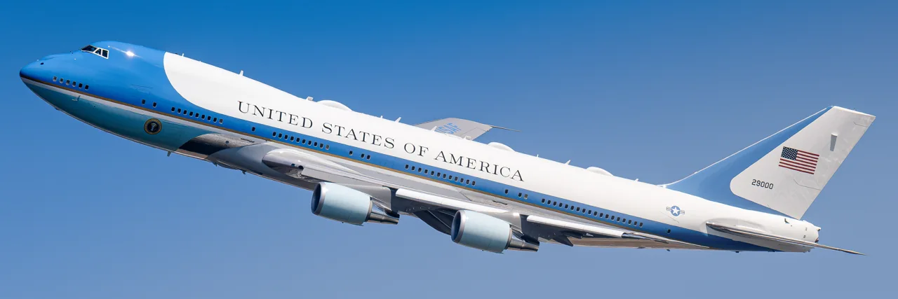 Air Force One climbing against a clear blue sky.