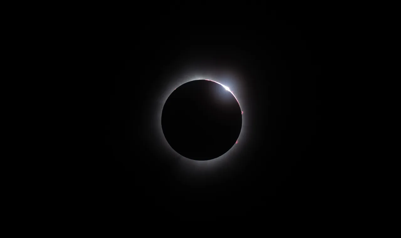 A total solar eclipse with a thin glowing corona against a black sky.